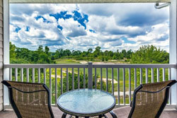 beautiful clouds and blue sky with green golf course views, 2 chairs, and a table, over a white railing, pet friendly vacation rental in myrtle beach
