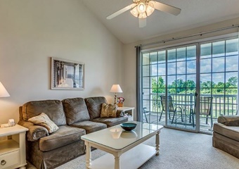living room with ceiling fan, couch, coffee table, and views of the golf course and balcony, myrtle beach pet friendly vacation rental home